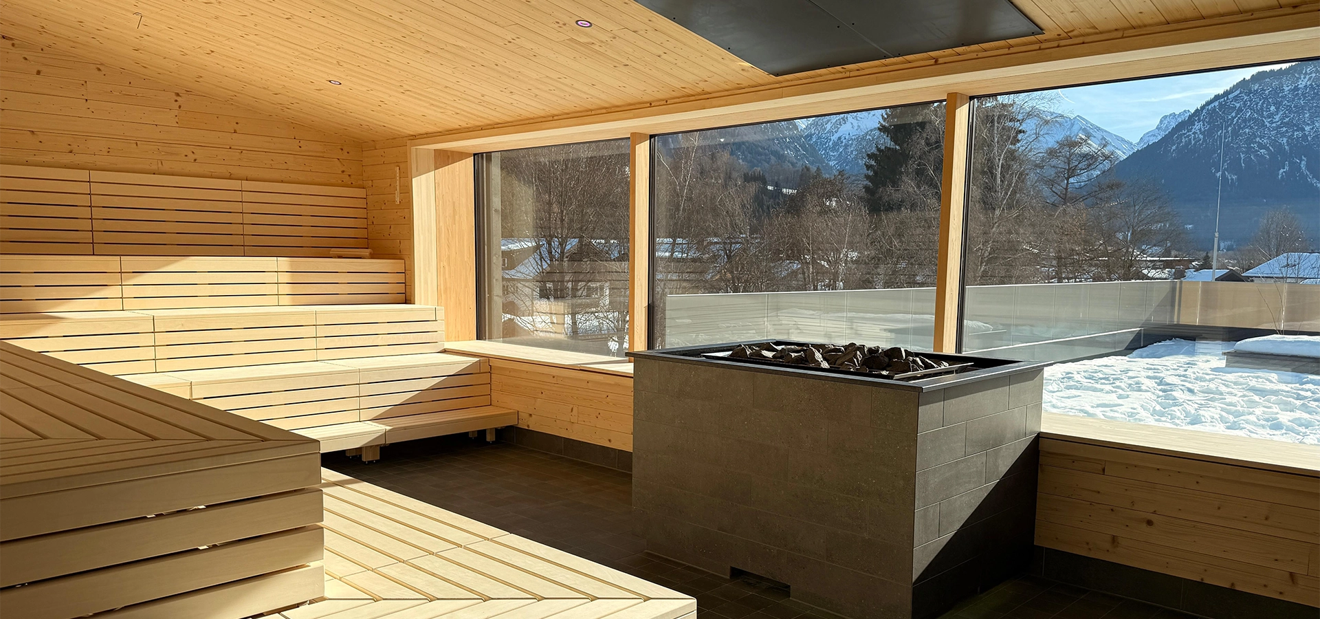 Aufgusssauna mit Saunaofen und Blick in den Außenbereich